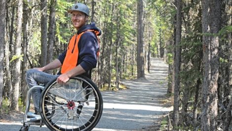man in wheelchair on trail in woods