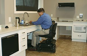 man in motorized chair at kitchen sink