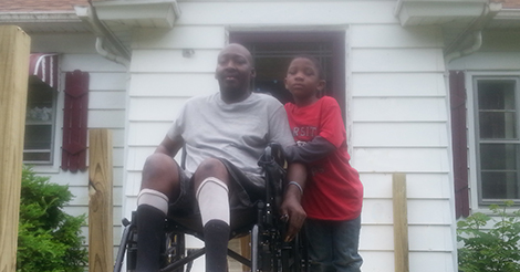 man in wheelchair with child outside their home