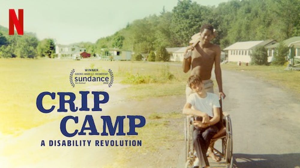 "Crip Camp" 2 young men, one pushing he other in a wheelchair outdoors