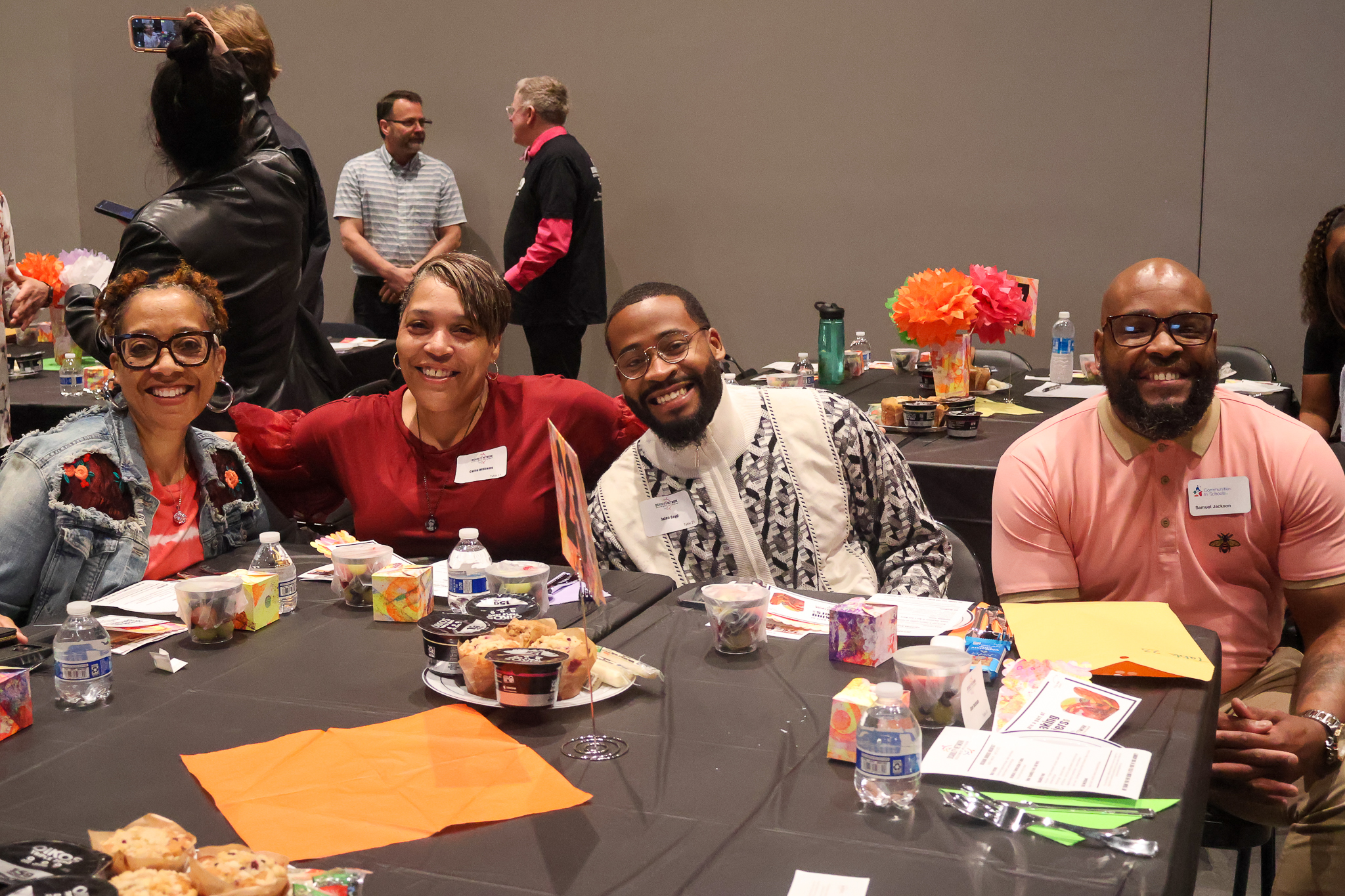 Four Black people seated at a breakfast table, smiling for the camera.