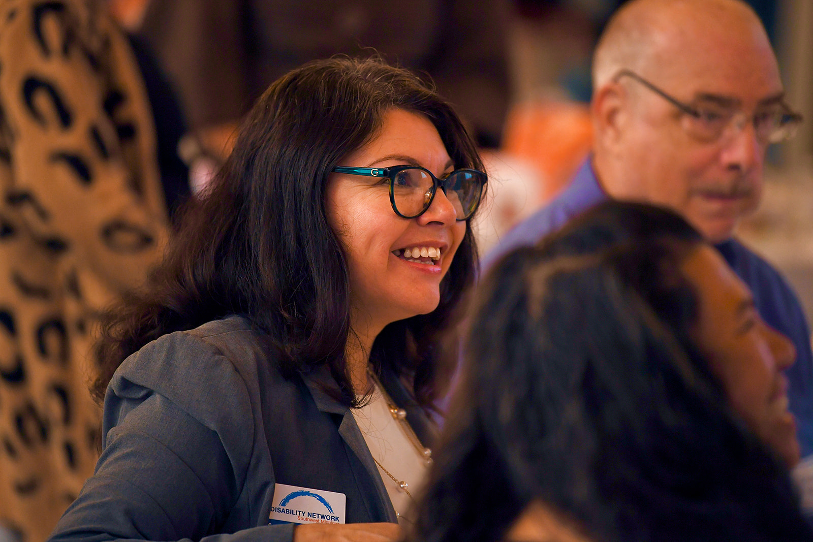 A Hispanic woman wearing a suit jacket and glasses.