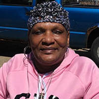 dark skinned woman wearing a hat and a pick hoodie