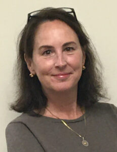 woman with sholder-length brown hair, light skin, eyeglasses on top of her head.