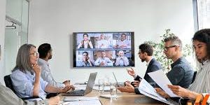 People in a meeting looking at monitor with virtual meeting participants.
