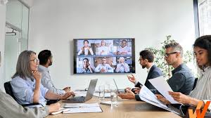 People in a meeting looking at monitor with virtual meeting participants.